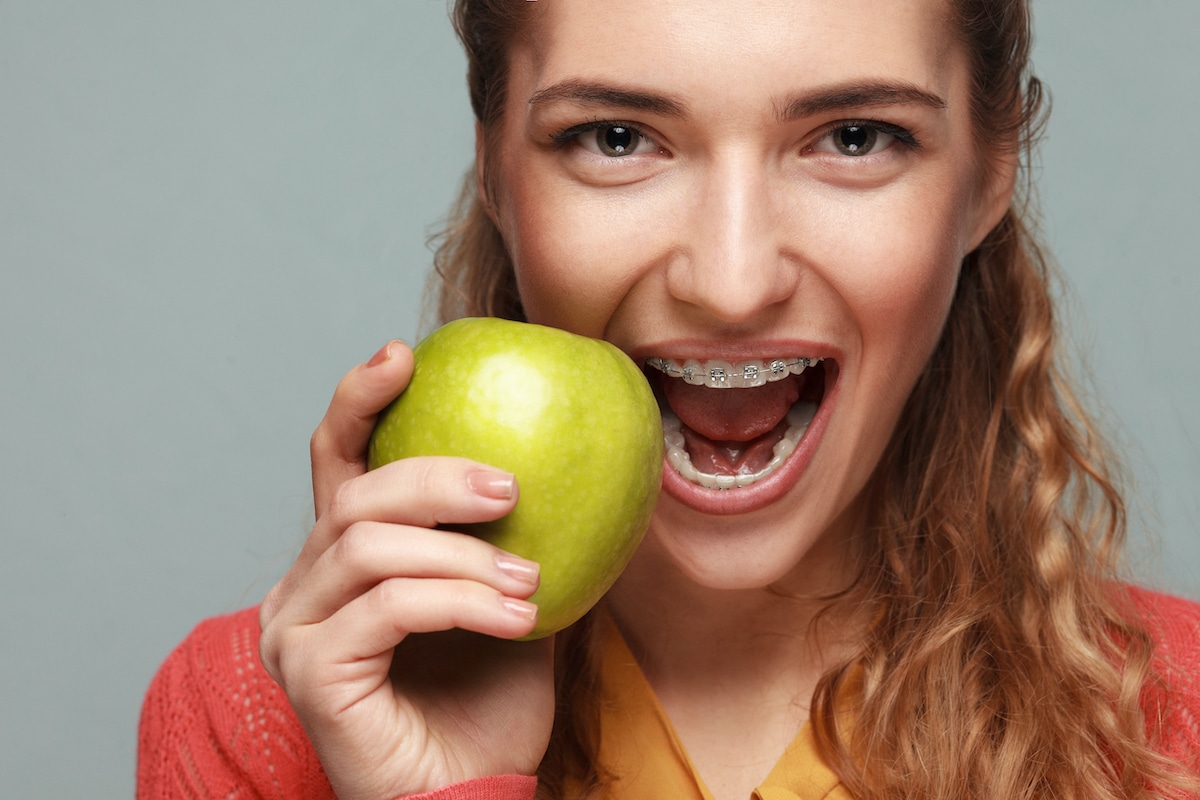 Woman with braces eating an apple